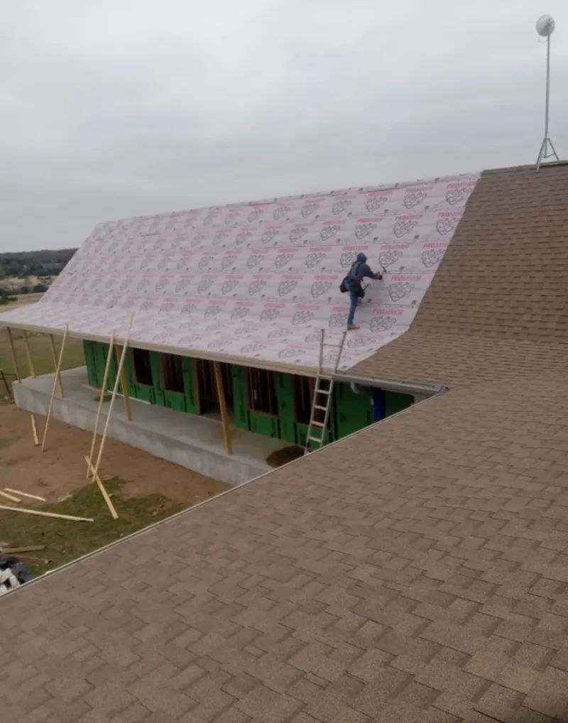 Worker preparing underlayment for a metal roof installation in Nitro